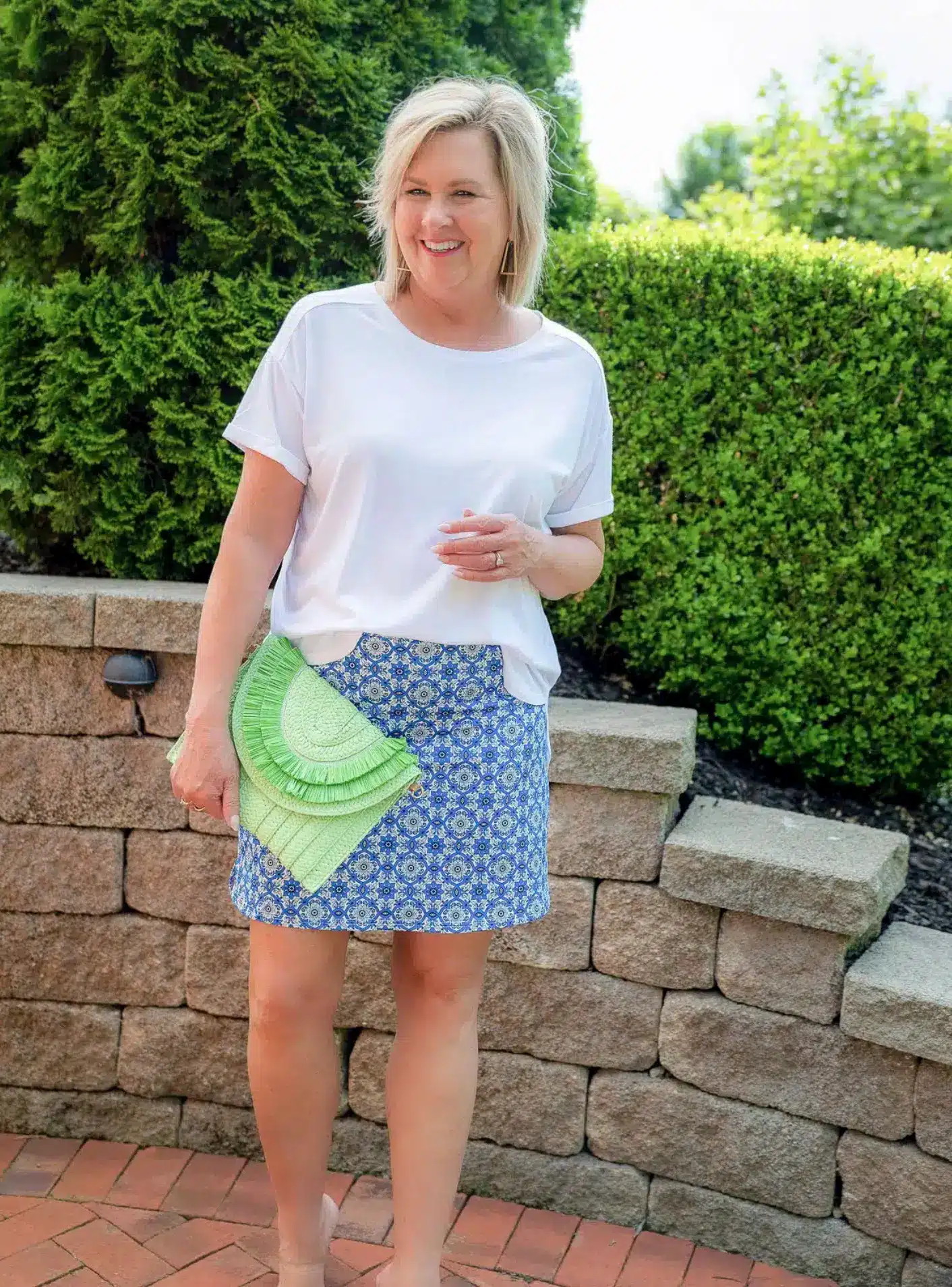 Tania Stephens wearing a lightweight white tee with an active skort and wedge sandals